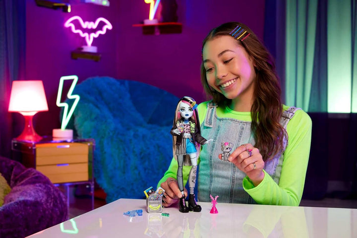Păpușă Monster High Frankie Stone cu jachetă din denim și pantaloni scurți, include câinele Watzie și accesorii precum un rucsac, o gustare și un notebook, HXH73 Papusi Naty Shop